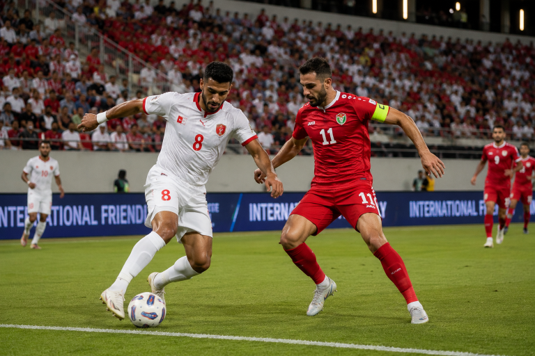 Two soccer players, white jersey number 8 and red jersey number 11, contest the ball on the field with a crowded stands backdrop.